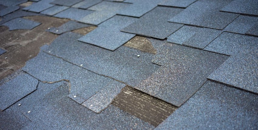 Сlose up view of bitumen shingles roof damage that needs repair.